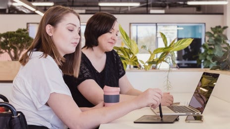 Two young women sitting in front of laptop.