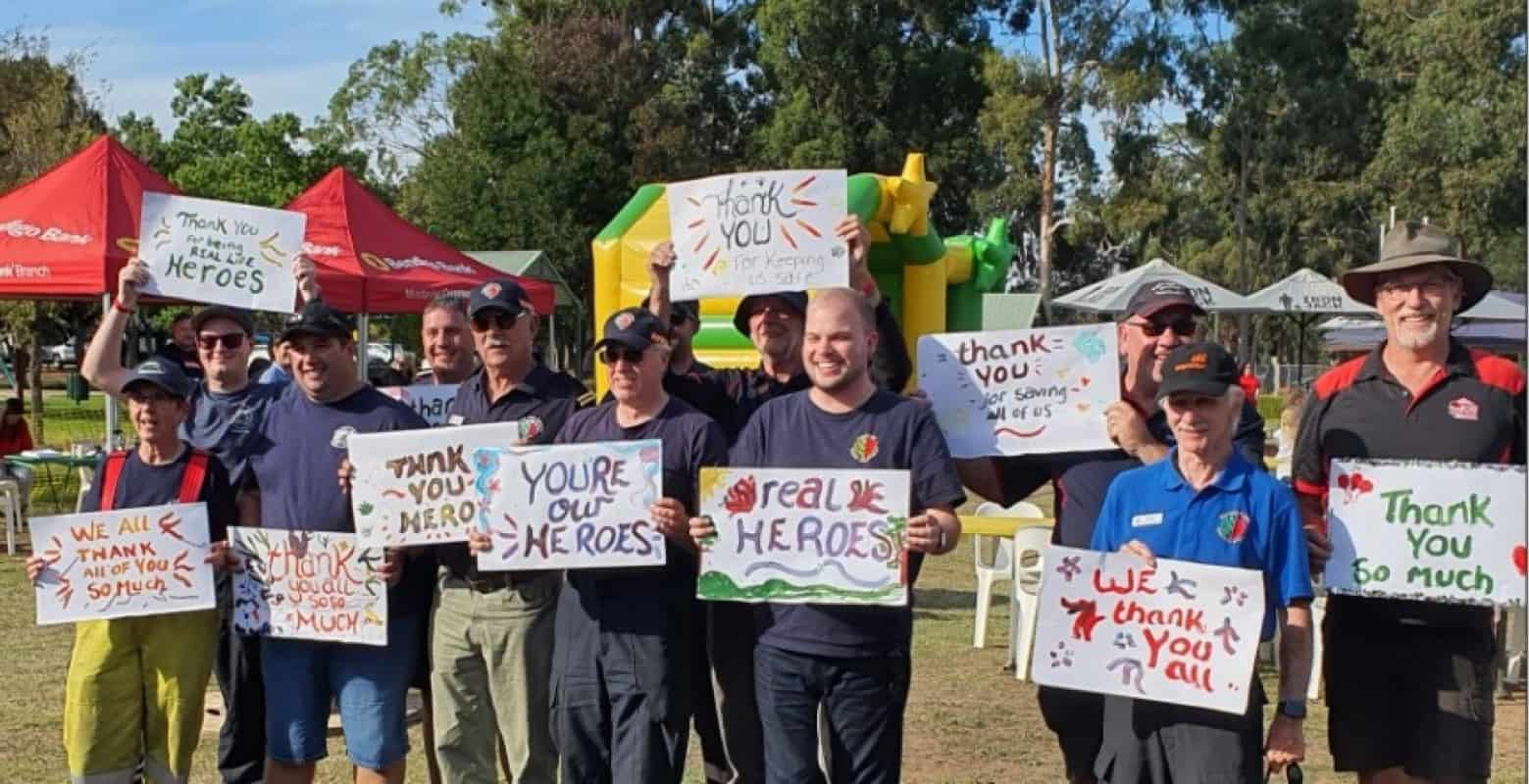 Image of group of firefighters holding cards with thank you messages from the community.