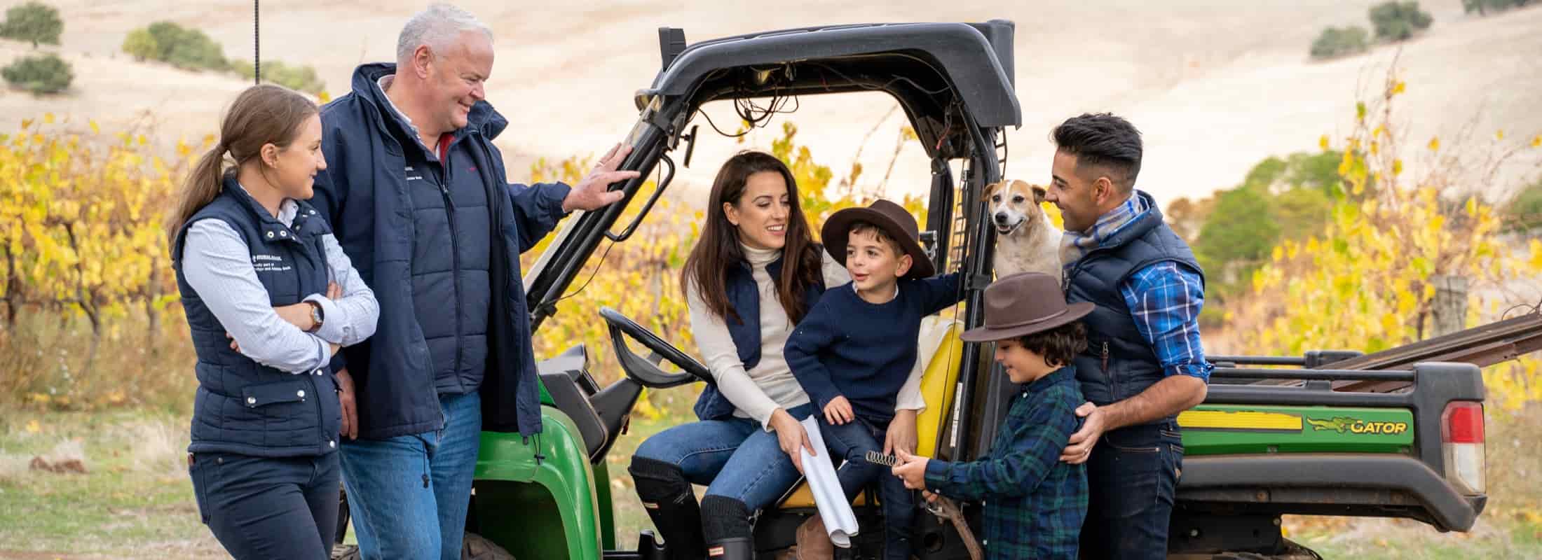 Image of rural family sitting and standing around farm equipment.