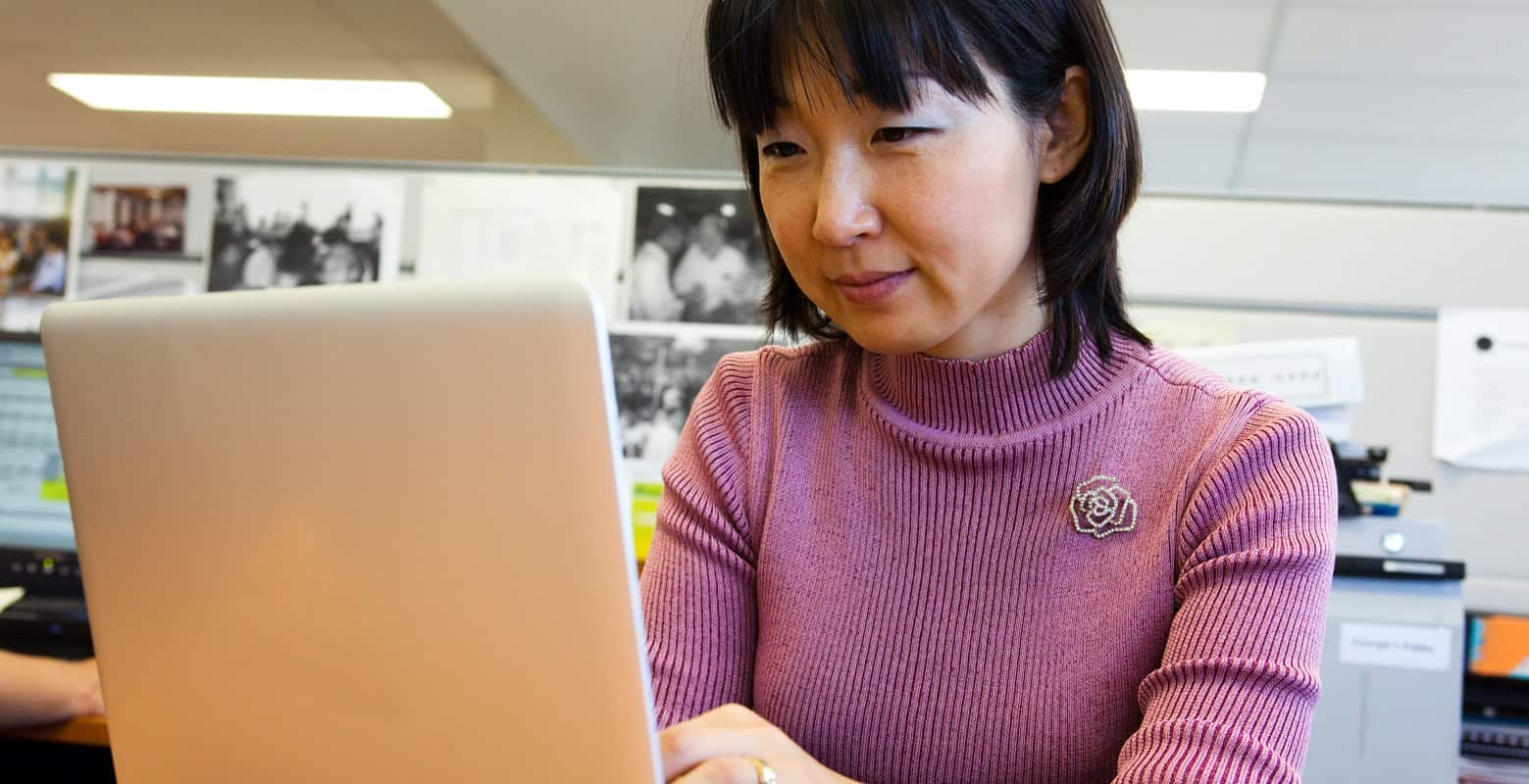 Woman sitting at desk looking at laptop